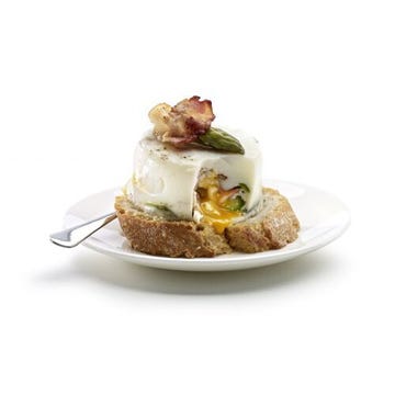 Poached eggs with bacon and green asparagus on toasted croutons in the oven